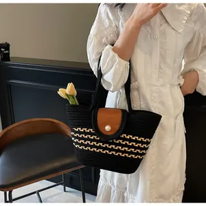 Detail of woven tote bag featuring a leather flap, pearl button, and striped pattern