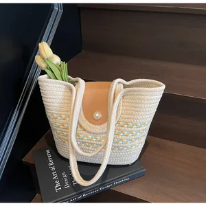 Detail of beige woven tote bag featuring brown leather flap and pearl accent on stairs