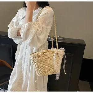 Détail d'un sac en paille tressée avec un nœud en dentelle blanche et doublure à cordon