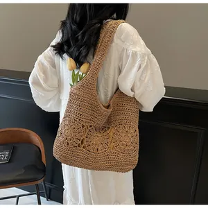 Detailed hollow woven texture of large brown straw shoulder bag with flower pattern