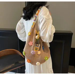 Dettaglio della borsa all'uncinetto marrone con fiori 3D colorati e tracolla a motivi