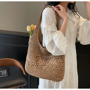 Detail of hand-woven straw tote bag with intricate floral hollow patterns and wide strap