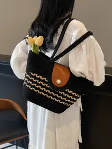 Striped woven shoulder bag with brown leather flap and pearl accent on white dress