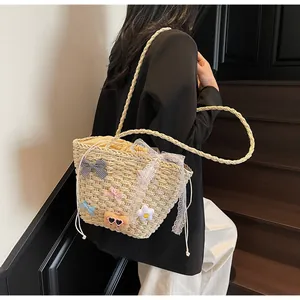 Détail d'un sac en paille avec nœud à carreaux et ours en peluche sur escalier