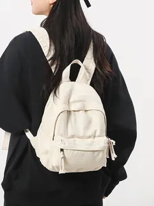 Crèmekleurige canvas mini rugzak voor dames in vintage stijl, achteraanzicht op model