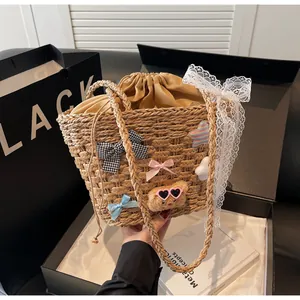 Détail d'un sac en paille avec nœuds en dentelle, ours en peluche et rubans