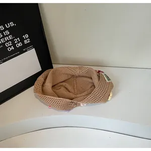 Dettaglio del berretto in maglia beige con ricami floreali colorati e finiture traforate