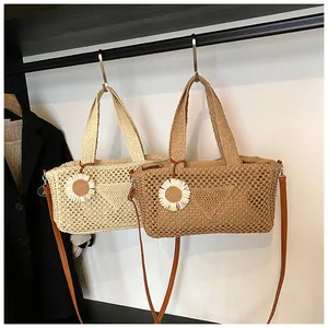 Dettaglio di borse tote in paglia intrecciata con ciondoli floreali e tracolle