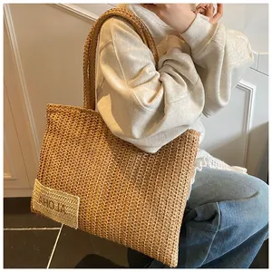 Dettaglio della borsa tote in paglia intrecciata con manici spessi e patch ALOHA boho