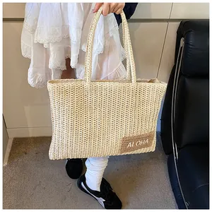 Dettaglio della borsa tote in paglia intrecciata con patch ALOHA e trama naturale