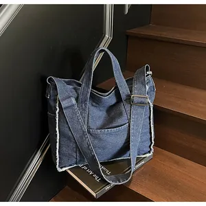 Detailed close-up of dark denim tote bag with frayed edges and adjustable strap