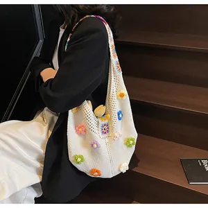 Dettaglio di una borsa tote in maglia bianca con fiori 3D all'uncinetto e tracolla colorata