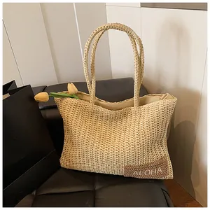 Dettaglio borsa in paglia con toppa ALOHA e tulipani gialli su uno sgabello di pelle nera