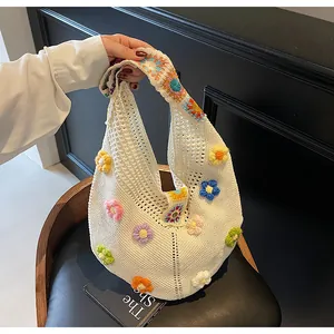 Dettaglio della borsa hobo all'uncinetto con fiori 3D colorati e tracolla in maglia