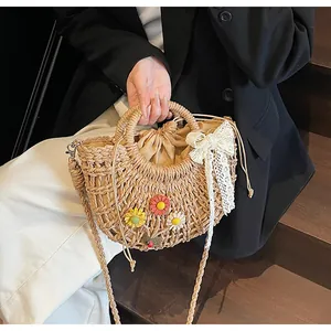 Detail of straw woven crescent bag with colorful floral decor and lace ribbon bow