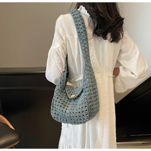 Detail view of grey-blue crochet hobo bag showing hollow knit pattern and wood button