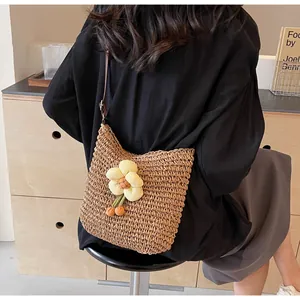 Detail der handgewebten Strohtasche mit Blumendekor an einer Modell-Schulter