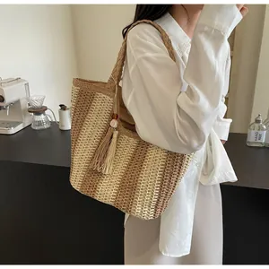 Close-up of a woven straw tote bag with boho tassel detail and wooden beads