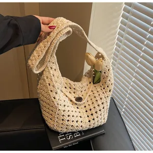 Detail of beige crochet knit shoulder bag with round button closure and floral decor