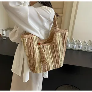 Detail of striped straw tote bag featuring decorative fringe and beaded tassel charm
