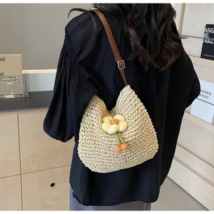 Detail einer Strohtasche mit gelber 3D-Blume und braunem Leder-Schultergurt