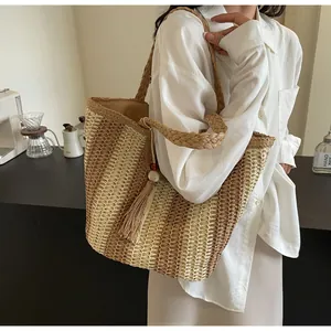 Detail of a striped straw tote bag with tassel charm in a minimalist cafe setting