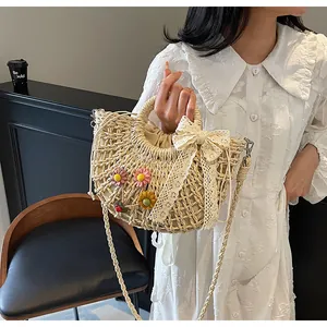 Detail of hand-woven straw bag with colorful crochet flowers and white lace bow accessory