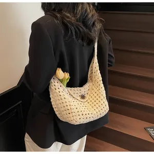 Detail of crochet shoulder bag featuring intricate hollow knit pattern and button closure