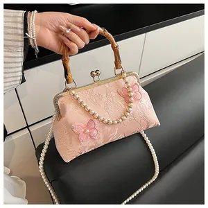 Close-up of pink jacquard shell bag with bamboo handle and 3D butterfly appliques