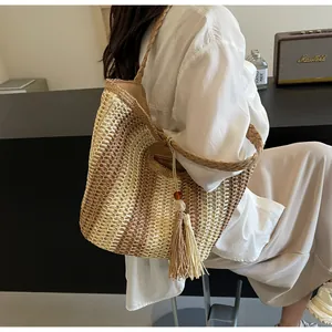 Detailed texture of hand-woven straw tote with striped pattern and decorative tassels