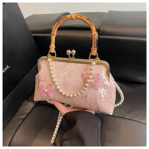 Detail of pink jacquard bag with bamboo handle, 3D butterfly appliques and pearl chain