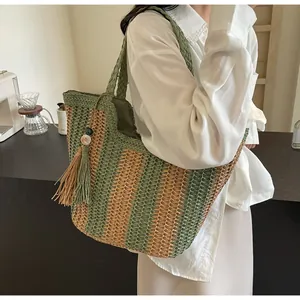Detail of hand-woven straw tote bag with green stripes and tassel charm accessory