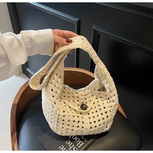Detail of cream crochet handbag featuring intricate knit patterns and a round wood button