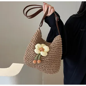 Detail der gewebten Strohtasche mit Blumendekor und verstellbarem braunem Leder-Schultergurt