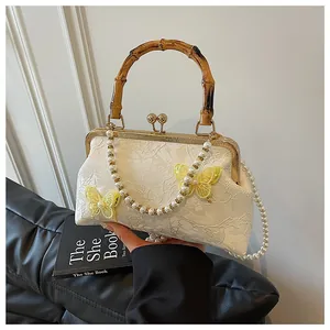 Detail of lace handbag with 3D yellow butterflies, bamboo handle and pearl chain strap