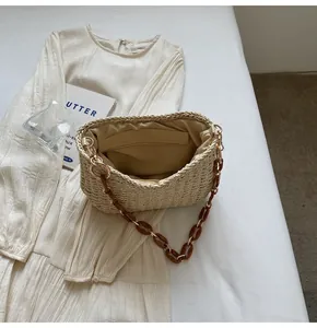 Close-up of beige woven straw bag featuring resin chain strap and fabric lining interior