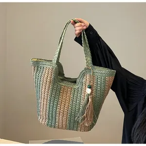 Close-up of green and tan striped straw woven bag with bead tassel and inner lining
