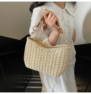 Detail of woven straw bag featuring amber acrylic chain handle and gold metal hardware