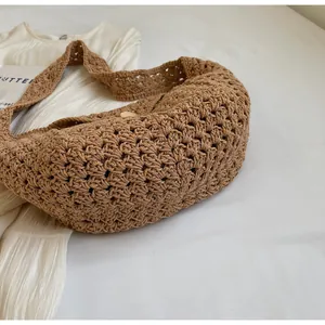 Detail of a brown crochet knit shoulder bag with hollow patterns and a wooden button