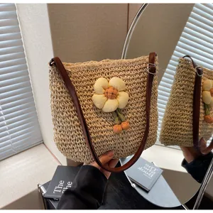 Detail der geflochtenen Strohtasche mit Blumendeko und braunem Lederriemen