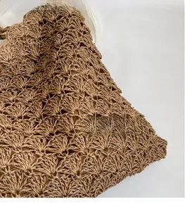 Close-up of brown straw bag featuring detailed hollow weave and fan-shaped texture