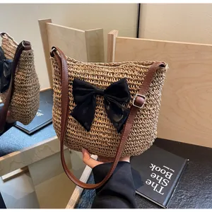 Detail der gewebten Strohtasche mit schwarzer Schleife und braunem Leder-Schultergurt