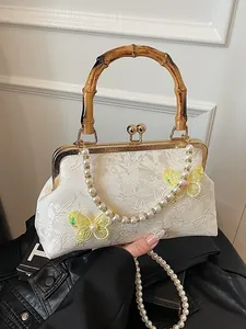 Lace handbag with bamboo handle, butterfly embroidery, and pearl shoulder strap detail