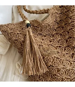 Detail of hollow-out straw bag with tassels and decorative wooden beads