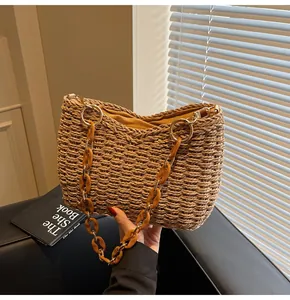 Detailed close-up of straw woven bag with amber resin chain strap and yellow lining