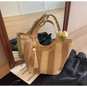 Detailed view of straw beach tote with gradient stripes and decorative tassel charm