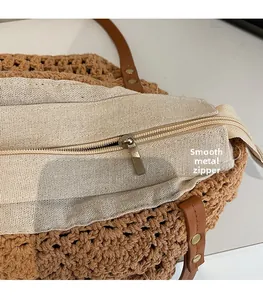 Detail of a smooth metal zipper and inner lining on a brown woven tote bag