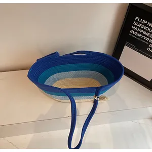 Détail d'un cabas tissé aux blocs de couleurs avec rayures bleues et pompon crème