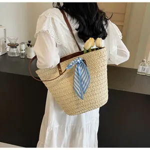 Detail of straw woven bucket bag with brown leather strap and striped silk scarf decoration