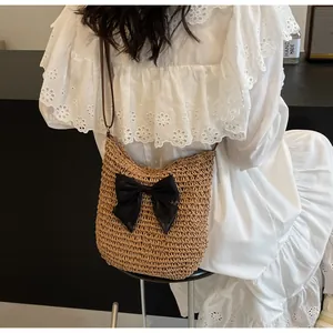 Detail der gewebten Stroh-Schultertasche mit schwarzer Schleife und Lederriemen